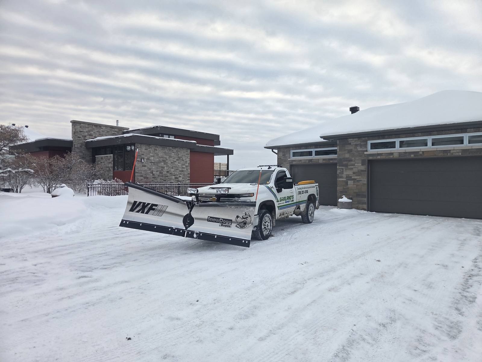 Garland's branded truck with SnowDogg plow clearing driveway